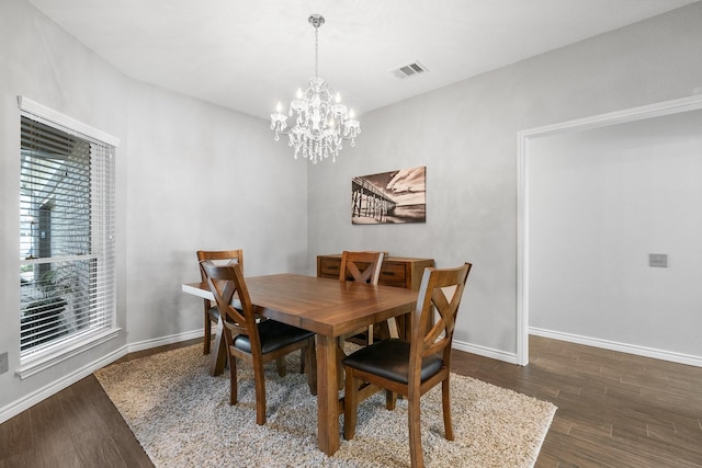 dining area with dark wood-type flooring and a chandelier