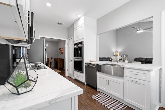 kitchen with white cabinetry, stainless steel appliances, kitchen peninsula, and light stone countertops