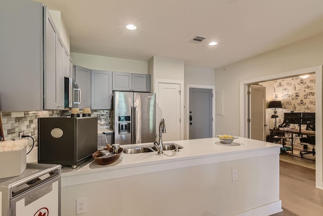 kitchen featuring sink, tasteful backsplash, gray cabinets, stainless steel appliances, and light hardwood / wood-style floors