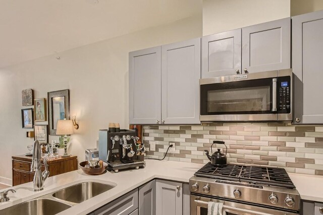 kitchen featuring sink, decorative backsplash, gray cabinets, and stainless steel appliances