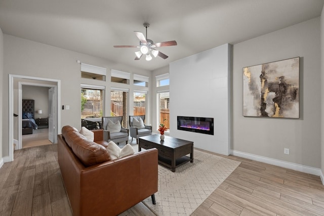 living room with ceiling fan, a fireplace, and light wood-type flooring