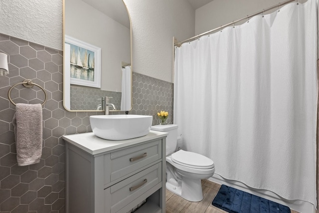 bathroom featuring hardwood / wood-style flooring, tile walls, vanity, toilet, and walk in shower