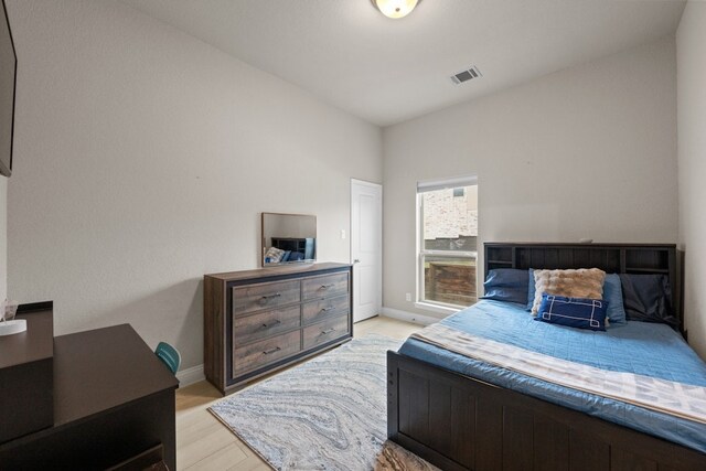 bedroom with lofted ceiling and light hardwood / wood-style floors