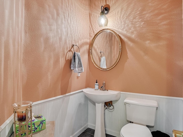 bathroom with wooden walls, tile patterned floors, and toilet