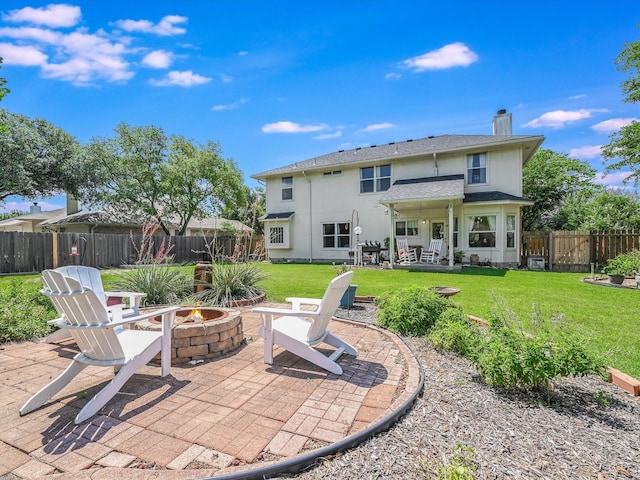 rear view of house featuring a yard, a patio area, and an outdoor fire pit