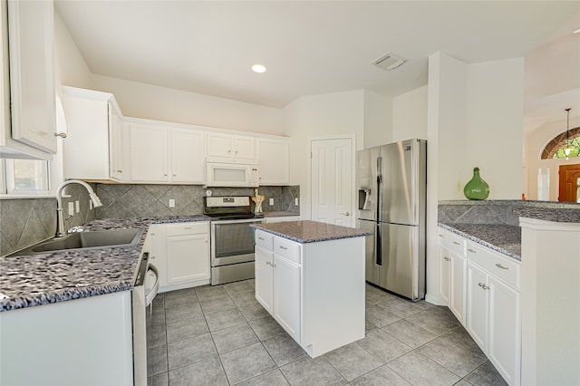 kitchen featuring a kitchen island, sink, white cabinets, dark stone counters, and stainless steel appliances