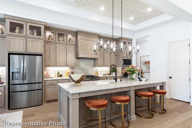1304 Jolie Rose Bnd, Leander, TX 78641 - kitchen with appliances with stainless steel finishes, tasteful backsplash, coffered ceiling, a kitchen island with sink, and light stone counters
