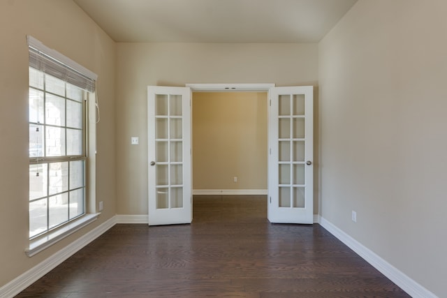 spare room with dark wood-type flooring, a wealth of natural light, and french doors