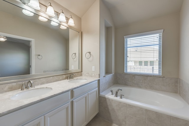 bathroom with vanity, lofted ceiling, and tiled bath