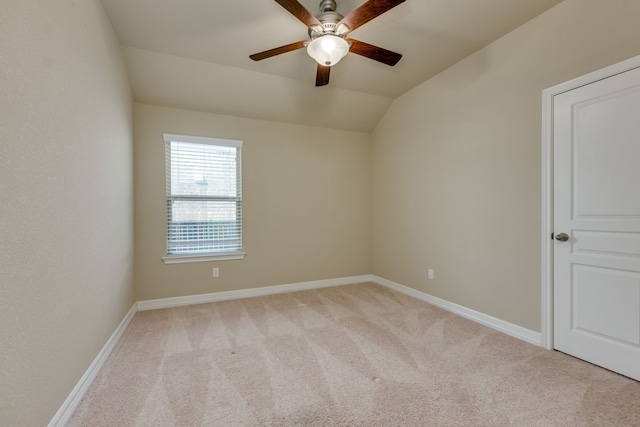 spare room featuring ceiling fan, vaulted ceiling, and light carpet