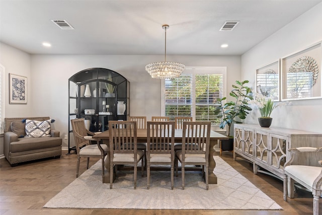 dining area with wood-type flooring and an inviting chandelier