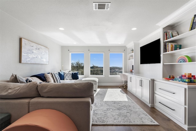 living room with hardwood / wood-style flooring, built in features, and a textured ceiling