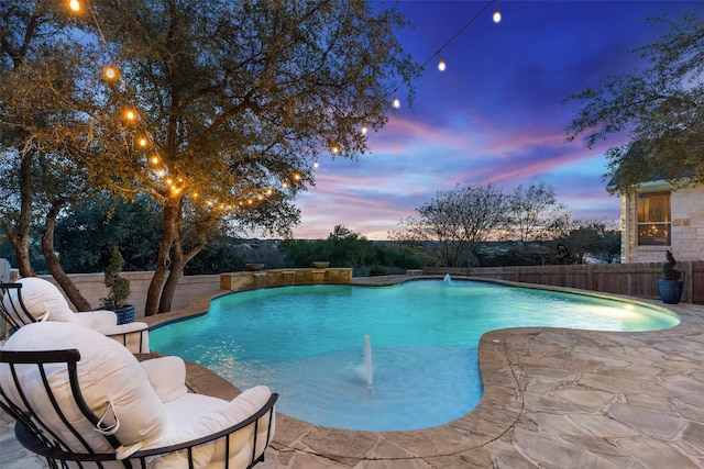 pool at dusk featuring a patio and pool water feature