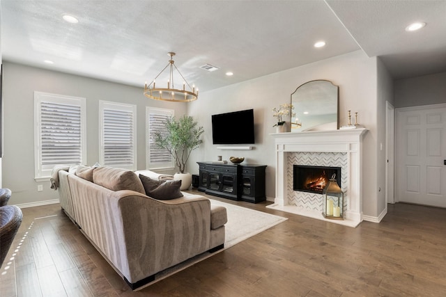 living room featuring an inviting chandelier, dark wood-type flooring, and a tile fireplace