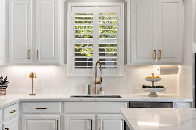 interior space with sink, backsplash, stainless steel dishwasher, and white cabinets