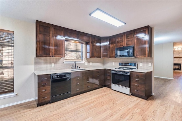 kitchen featuring dark brown cabinetry, light hardwood / wood-style floors, sink, and black appliances