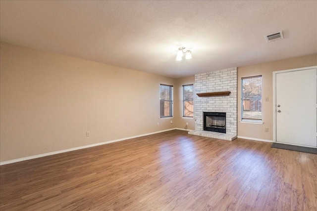 unfurnished living room featuring hardwood / wood-style flooring, a fireplace, and a textured ceiling