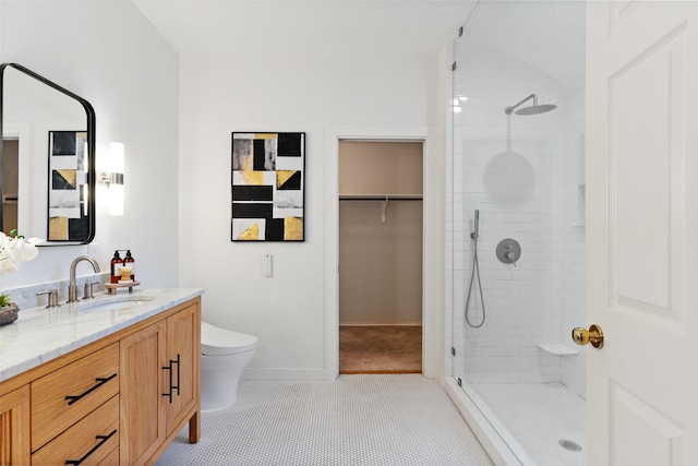 bathroom with a shower with door, vanity, tile patterned floors, and toilet