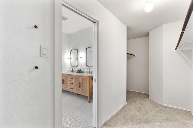 walk in closet featuring sink and light carpet