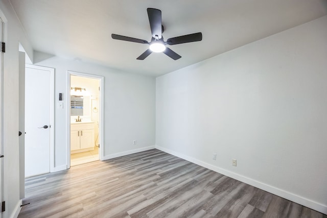 unfurnished bedroom featuring ceiling fan, ensuite bathroom, sink, and light hardwood / wood-style flooring