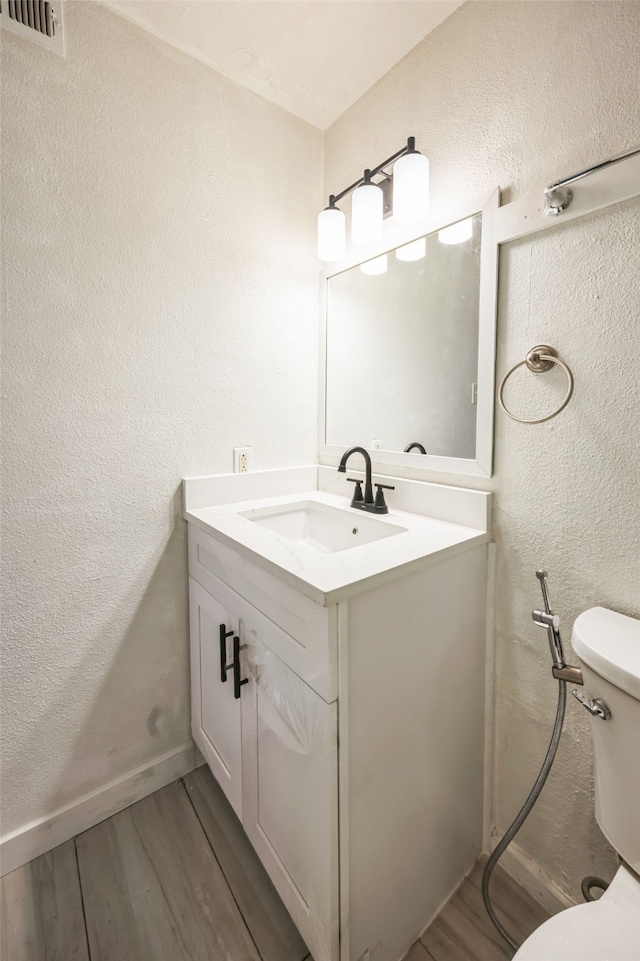 bathroom featuring vanity, hardwood / wood-style floors, and toilet