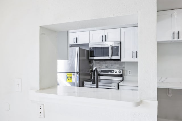 kitchen featuring backsplash, white cabinets, and appliances with stainless steel finishes