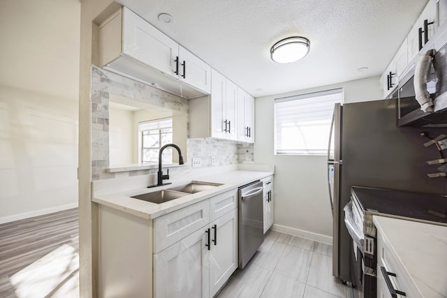 kitchen featuring sink, appliances with stainless steel finishes, a textured ceiling, white cabinets, and decorative backsplash