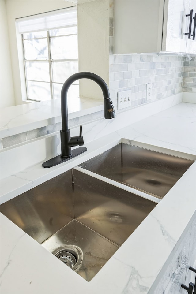 details with light stone countertops, sink, and backsplash