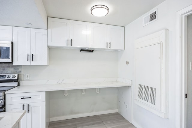 kitchen with appliances with stainless steel finishes, white cabinets, and light stone counters