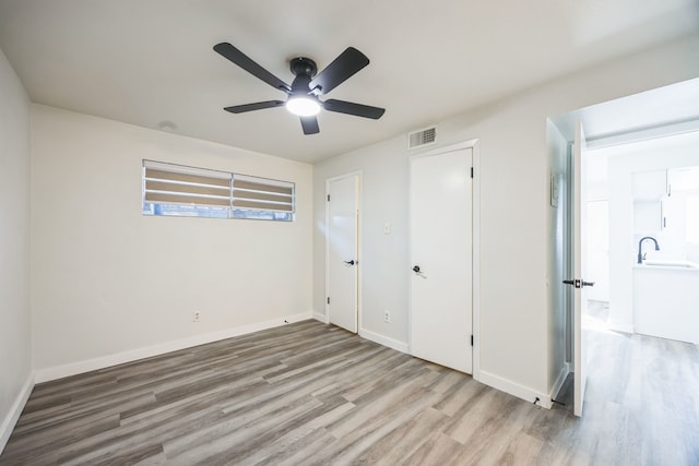 unfurnished bedroom with sink, light hardwood / wood-style floors, a closet, and ceiling fan