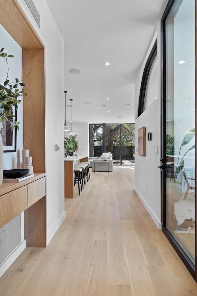 hallway with light hardwood / wood-style floors and expansive windows