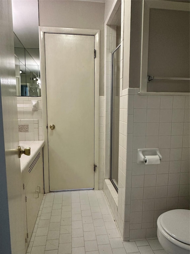 bathroom featuring tile patterned floors, toilet, an enclosed shower, and tile walls