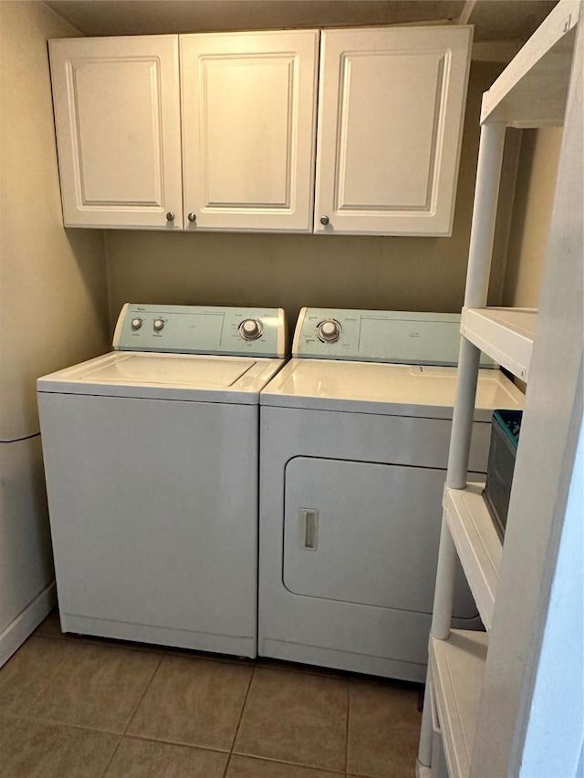 washroom with cabinets, dark tile patterned flooring, and washing machine and dryer