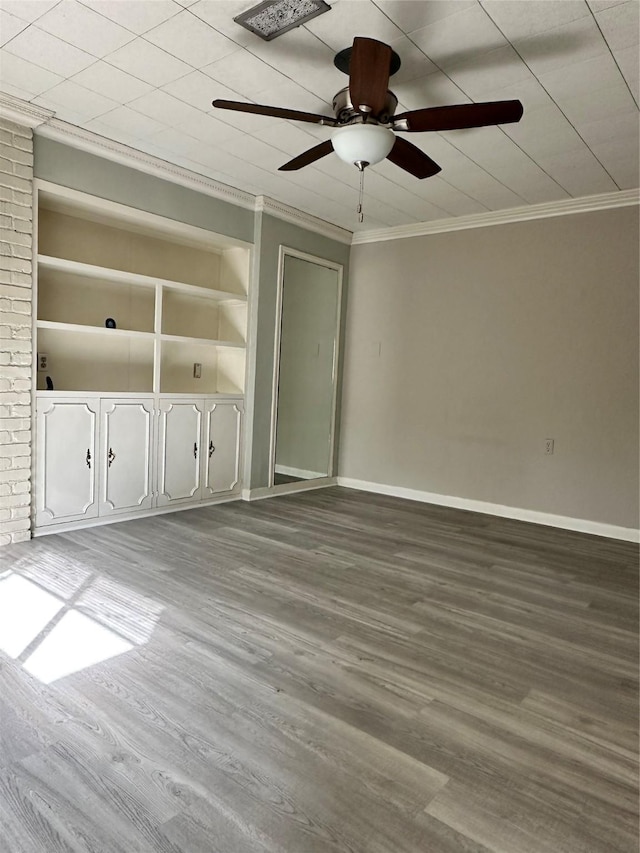 spare room featuring built in shelves, ceiling fan, ornamental molding, and wood-type flooring