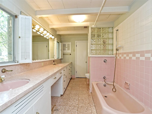 full bathroom with tiled shower / bath combo, vanity, beam ceiling, and toilet