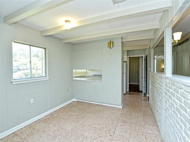 unfurnished room with beam ceiling