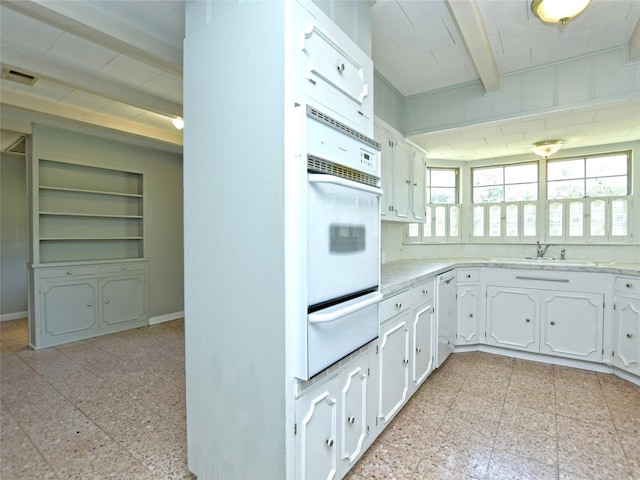 kitchen with sink, white appliances, beamed ceiling, and white cabinets