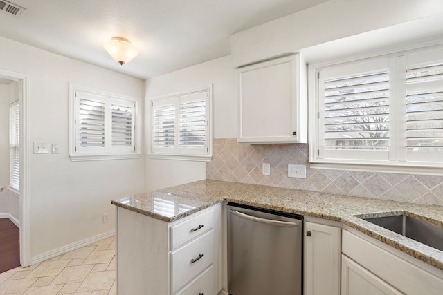 kitchen featuring backsplash, light stone counters, white cabinets, stainless steel dishwasher, and kitchen peninsula