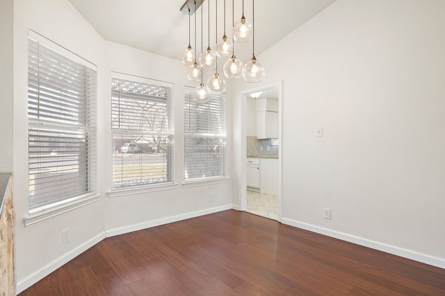 unfurnished dining area featuring dark wood-type flooring and vaulted ceiling