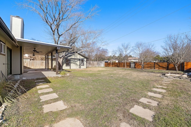 view of yard featuring an outbuilding, ceiling fan, and a patio area