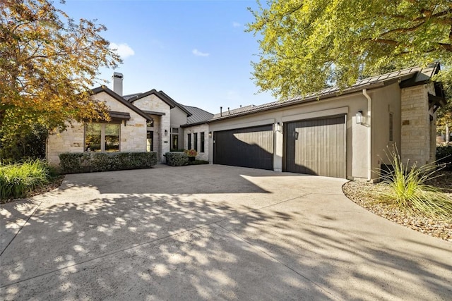 view of front of property with stone siding, concrete driveway, an attached garage, and a standing seam roof