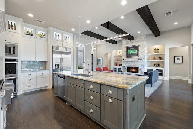 kitchen featuring built in appliances, sink, beamed ceiling, and white cabinets