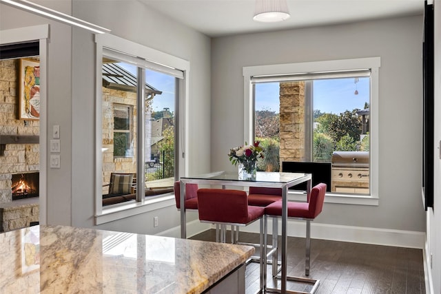 dining area featuring dark hardwood / wood-style flooring and a stone fireplace