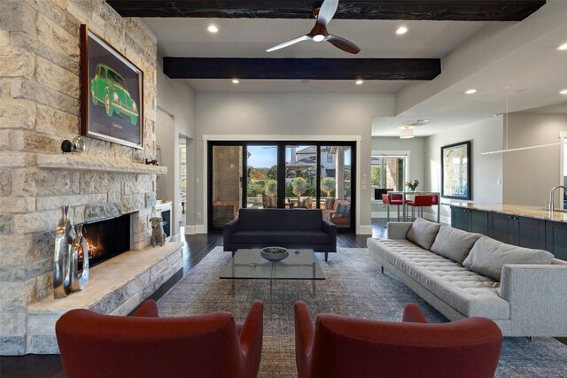 living room with beamed ceiling, ceiling fan, dark hardwood / wood-style floors, and a fireplace