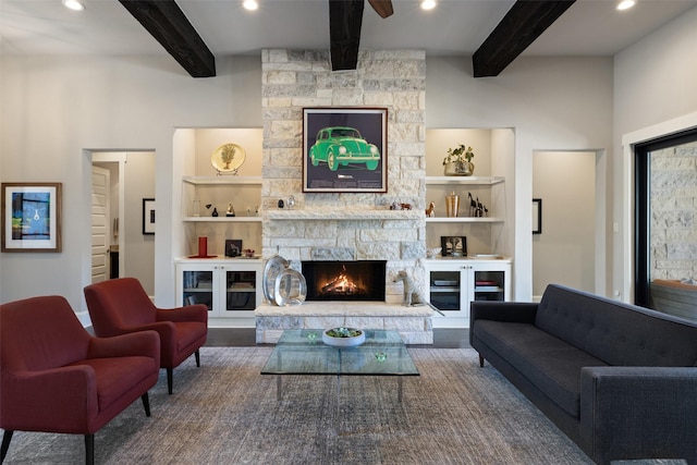 living room with hardwood / wood-style floors, beam ceiling, a stone fireplace, and ceiling fan