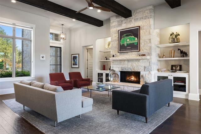 living room featuring dark hardwood / wood-style flooring, beam ceiling, a fireplace, and built in features