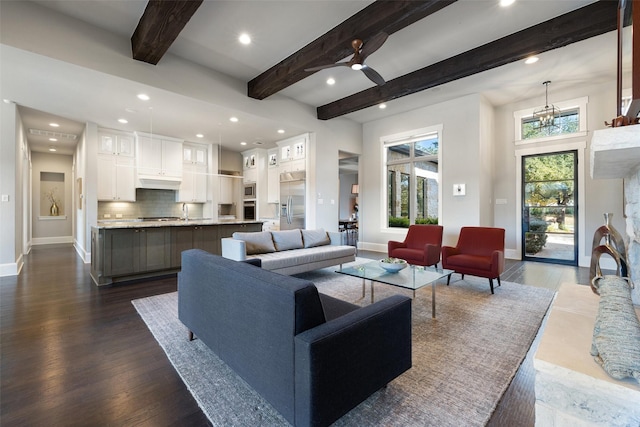 living room with dark hardwood / wood-style flooring, beam ceiling, and ceiling fan with notable chandelier