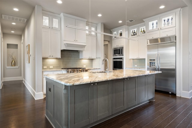 kitchen featuring a large island, built in appliances, and white cabinets