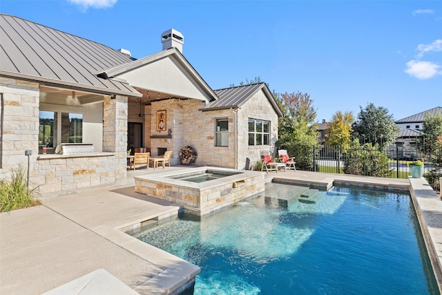 view of swimming pool featuring an in ground hot tub, exterior bar, a patio, and an outdoor stone fireplace