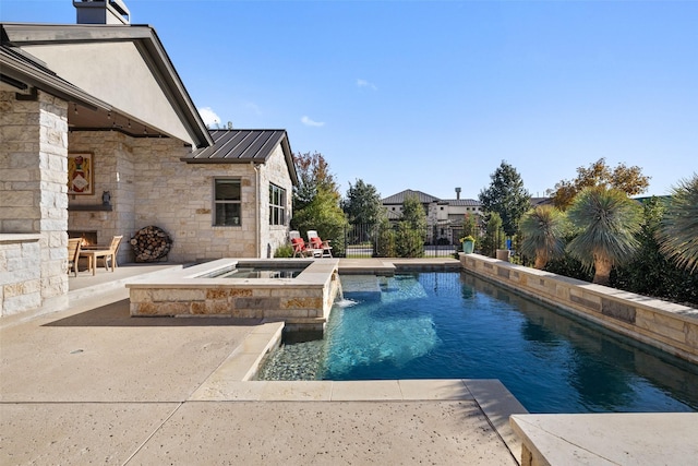 view of swimming pool featuring a patio area, pool water feature, and an in ground hot tub